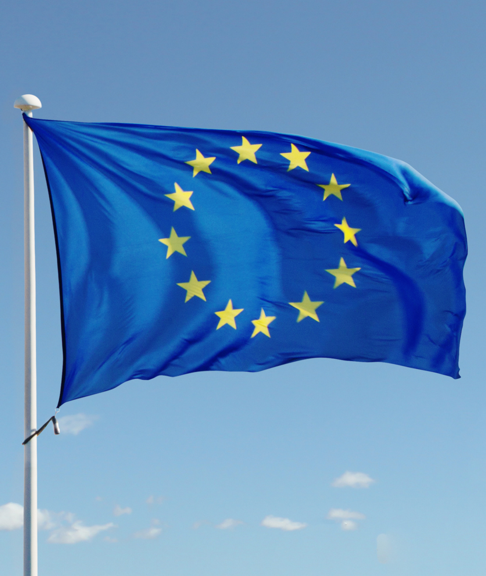 EU flag waving against blue sky with clouds.